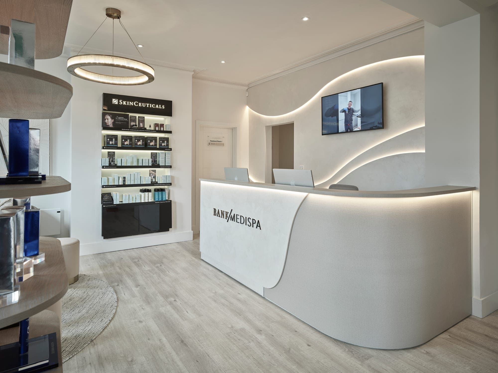 Reception at Bank Medi Spa in Hale, with a curved illuminated desk and backlit product shelving