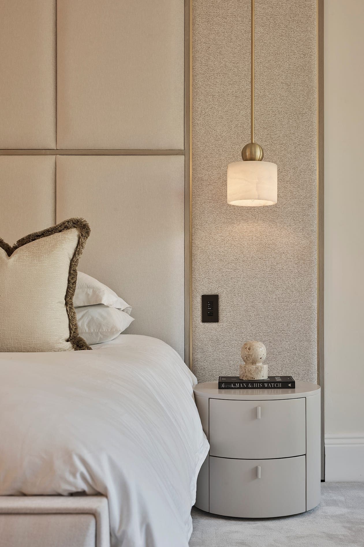 Principal bedroom detail with a fringed cushion and a textured wall panel, Prestbury family home